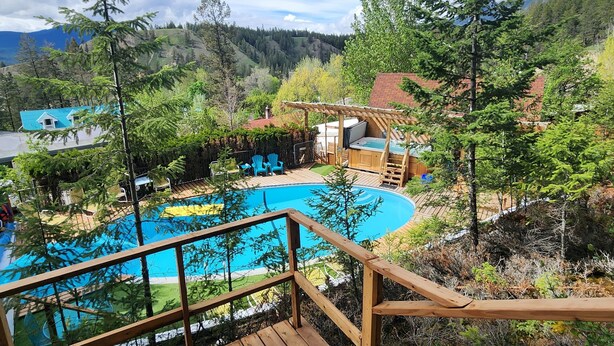 A wooden deck leading to a swimming pool with a mountain backdrop. - Motel Tyrol (Radium Hot Springs)