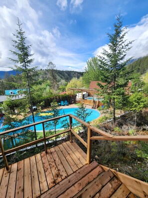 A wooden deck leading to a swimming pool with a mountain backdrop. - Motel Tyrol (Radium Hot Springs)