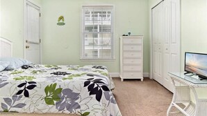 Un dormitorio con una cama, un aparador, un televisor y un armario.