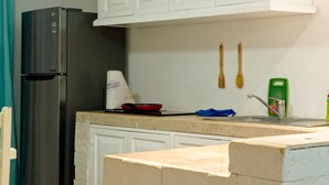 Eine Küche mit Kühlschrank, Spüle und Holzkochlöffeln auf der Arbeitsfläche.