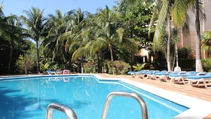 Ein Swimmingpool mit blauem Wasser, umgeben von Palmen und Liegestühlen.