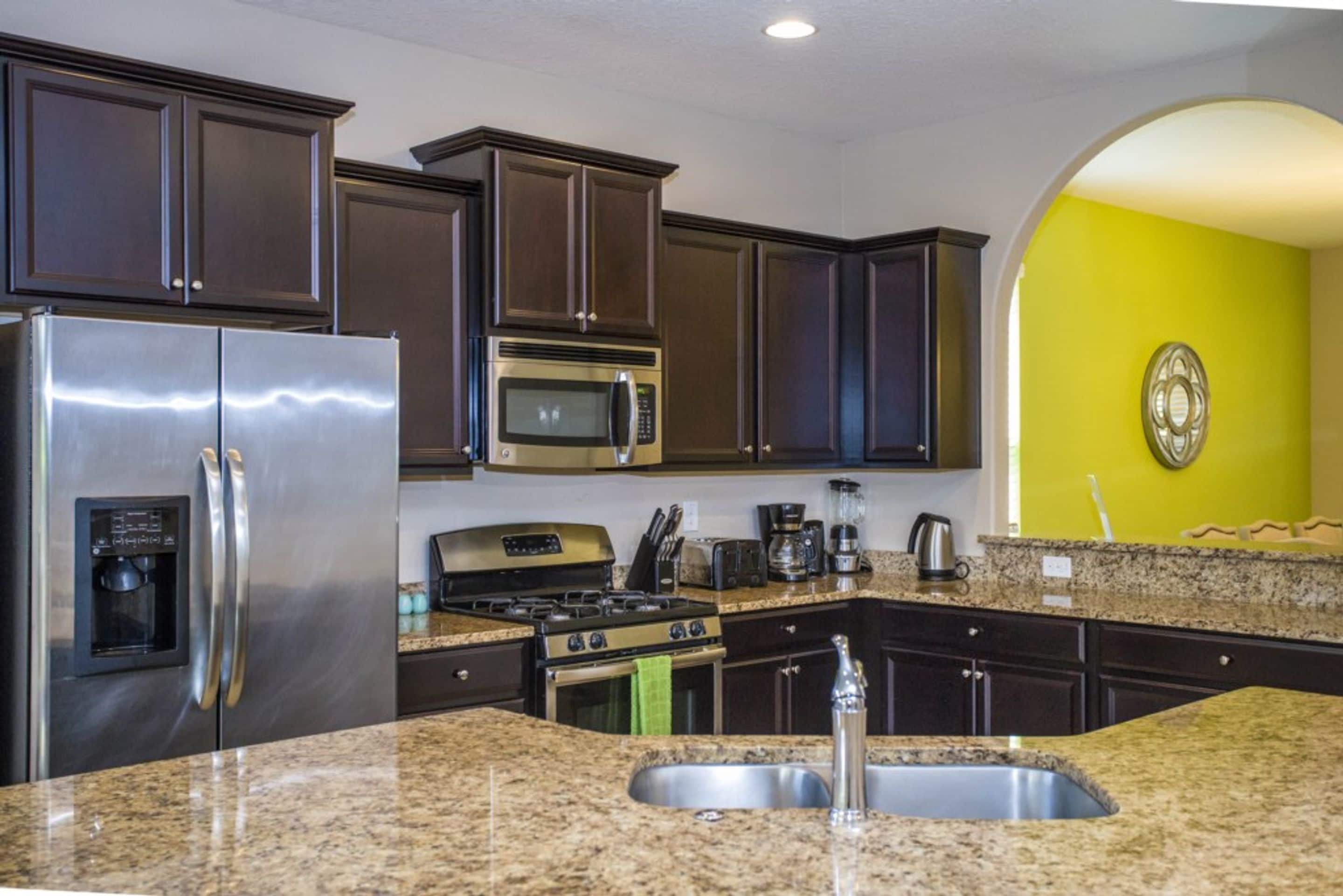 A modern kitchen with stainless steel appliances, dark cabinets, and a granite countertop.