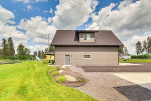 A two-story house with a grey exterior, a small window on the upper floor, and a garage door. - Creekside Apartment in Kalispell on 5 Acres (Kalispell)