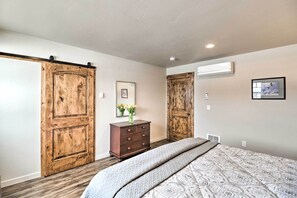 A bedroom with a large bed, wooden wardrobe, and a dresser with a vase of flowers. - Creekside Apartment in Kalispell on 5 Acres (Kalispell)