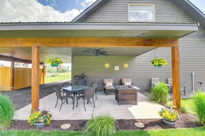 A covered patio area with a table and chairs, a grill, and hanging flower baskets. - Creekside Apartment in Kalispell on 5 Acres (Kalispell)