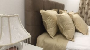 Une chambre à coucher avec un lit, des oreillers, une table de chevet et une lampe.