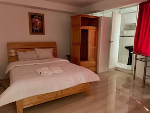 A bedroom with a wooden bed, a wardrobe, and a bathroom visible through an open door. - Hotel Plateros (Cusco)