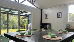 Un comedor con una mesa de madera oscura, sillas verdes y cuencos verdes sobre individuales.