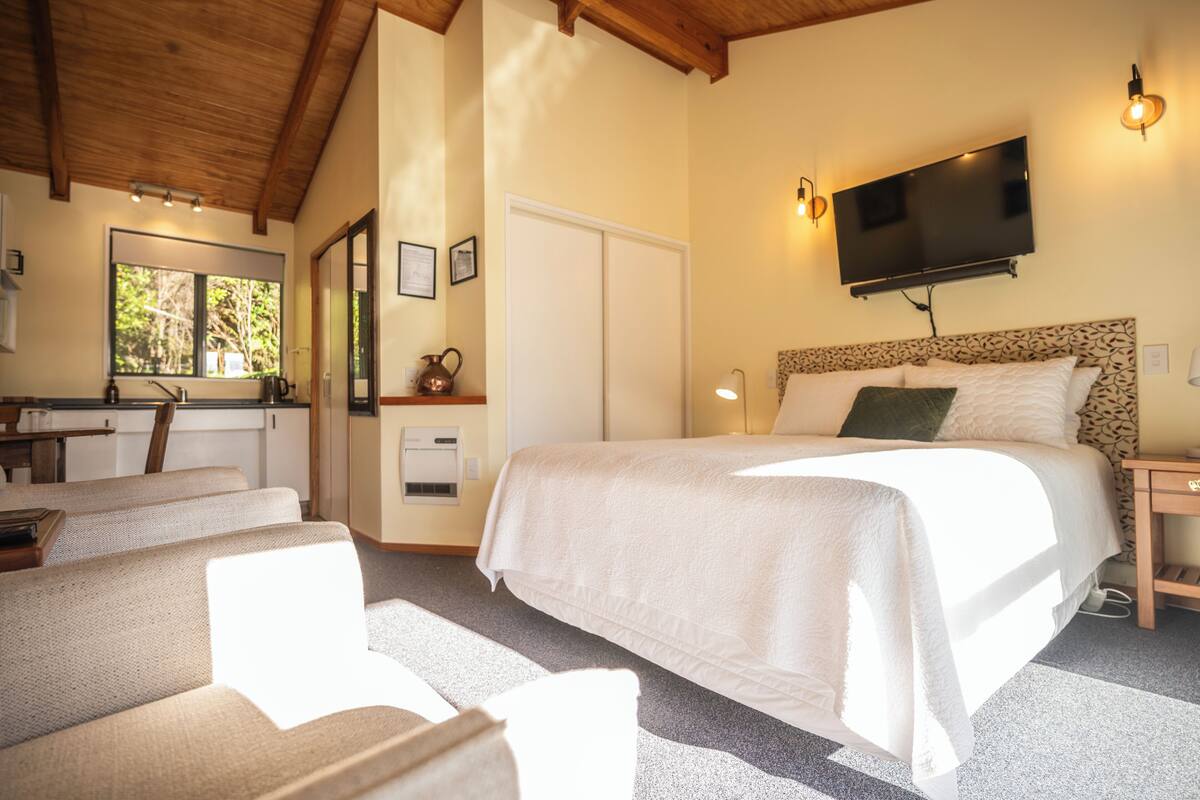 A bedroom with a bed, a TV, a desk, and a chair.