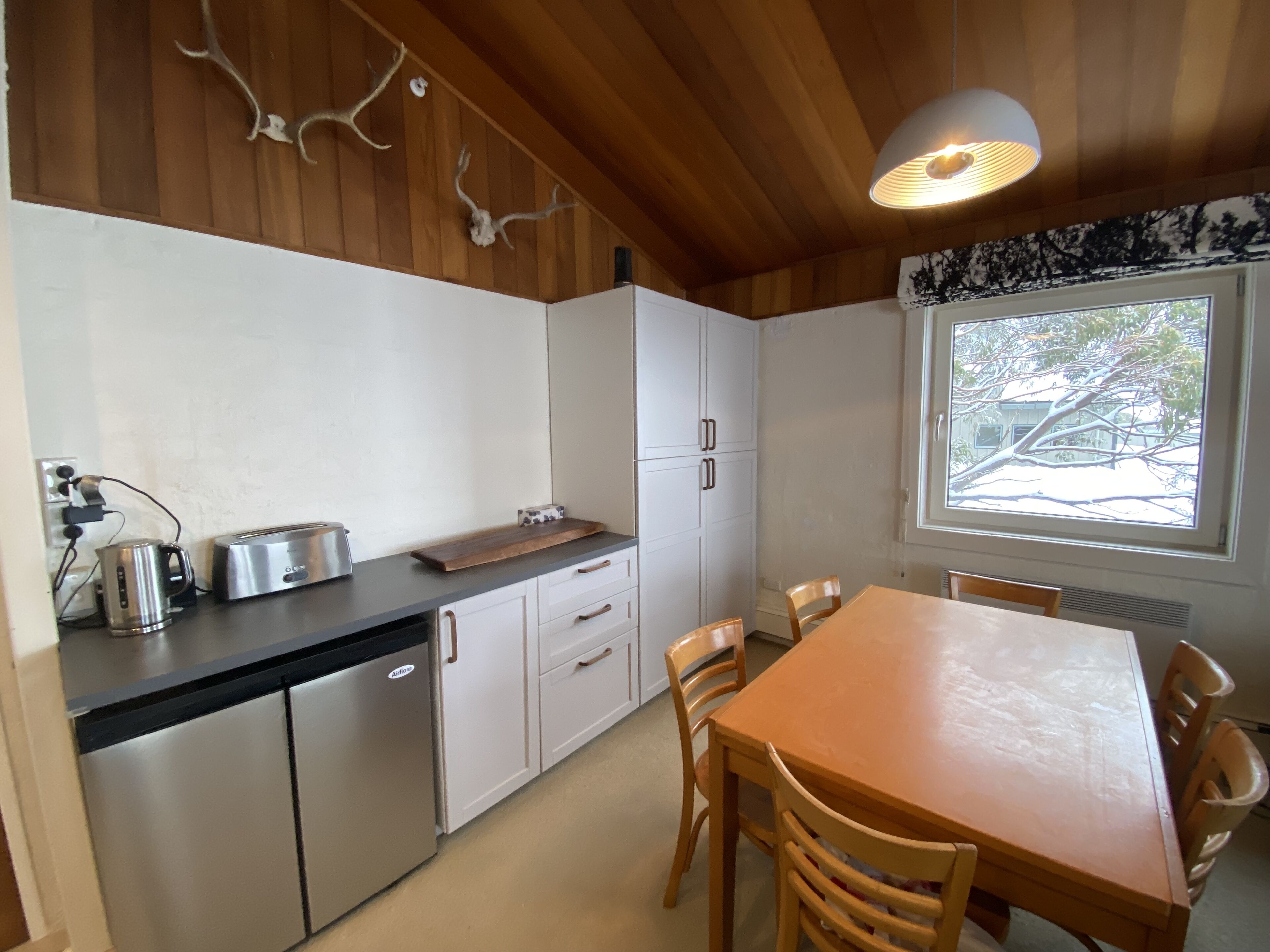 A compact kitchen with white cabinets, a wooden countertop, and a dining table with chairs.