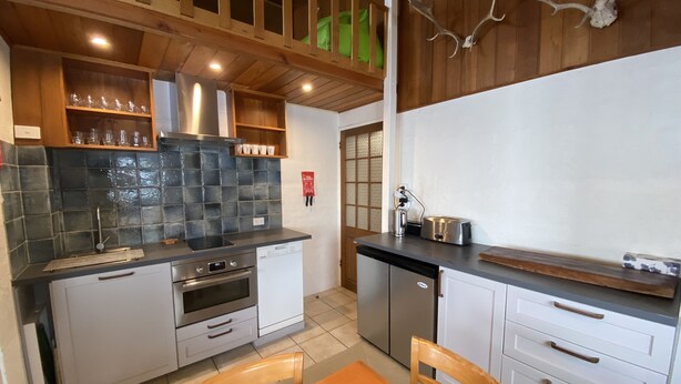 Una cocina moderna con horno integrado, lavavajillas y una mesa de comedor de madera con sillas.