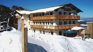 Un hotel de varios pisos con balcones, paisajes nevados y un cielo azul despejado.
