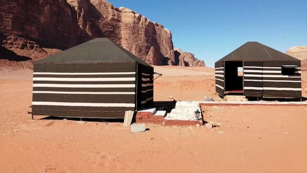 Two striped tents in a desert with rocky cliffs in the background. - Atlantis Rum Camp (Wadi Rum)