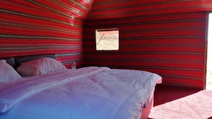 A room with a bed, a window, and red patterned walls. - Atlantis Rum Camp (Wadi Rum)