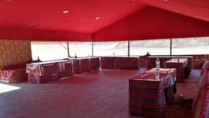 A tented room with cushioned seating and tables, a patterned wall, and a view of a snowy landscape. - Atlantis Rum Camp (Wadi Rum)