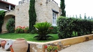 Un bâtiment en pierre doté d’un jardin, comprenant des pots en terre cuite et un petit étang.