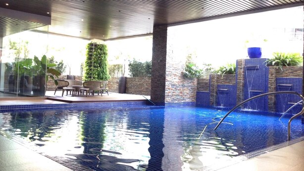 Una piscina amb cantell de rajola, envoltada per una zona de terrassa amb cadires i una taula.