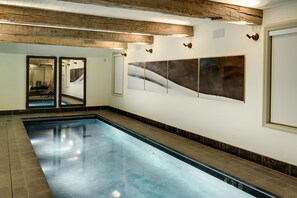 A swimming pool with a tiled border, wooden ceiling beams, and wall-mounted artwork. - Eleven Scarp Ridge Lodge (Crested Butte)