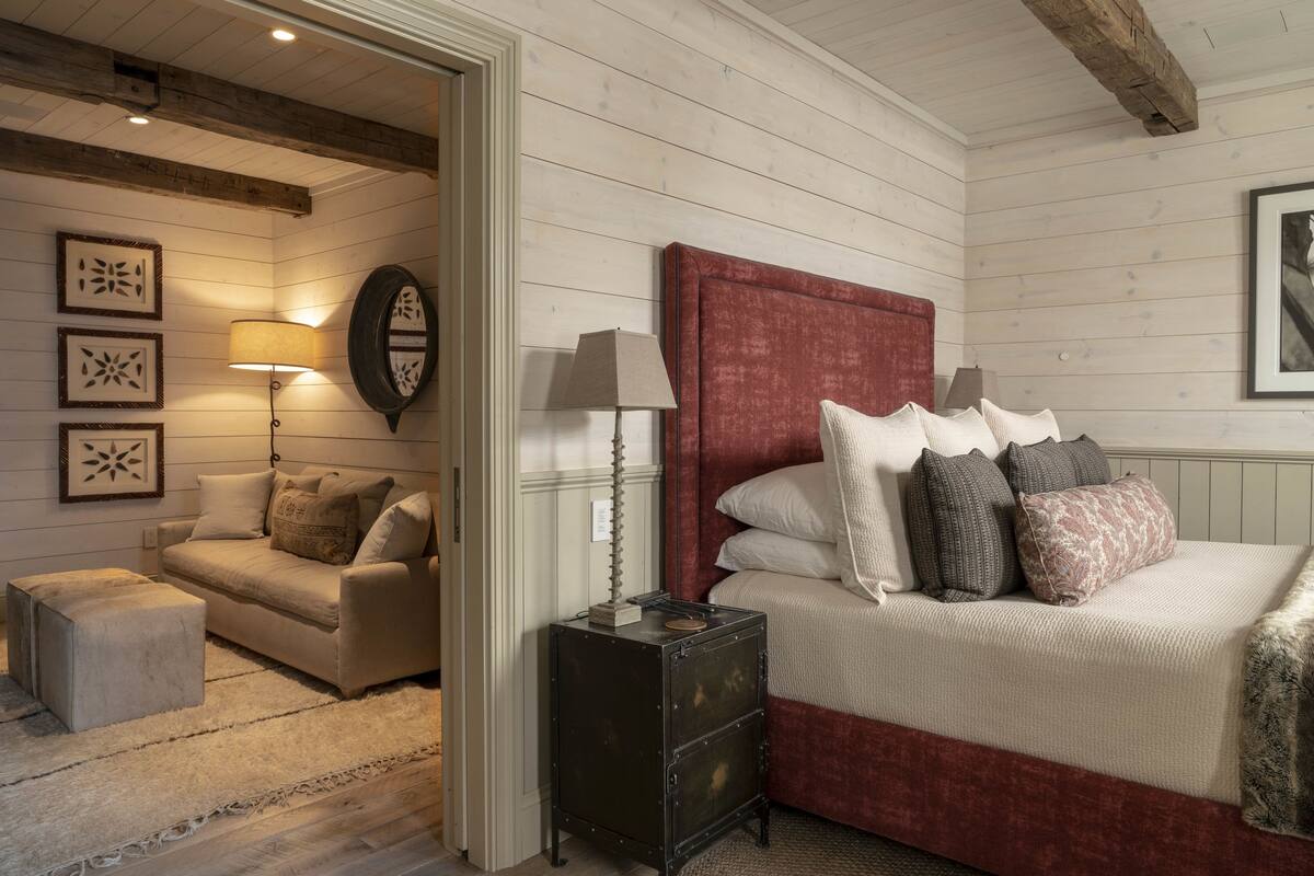 A bedroom with a bed, a nightstand, a lamp, a sofa, and a small table.