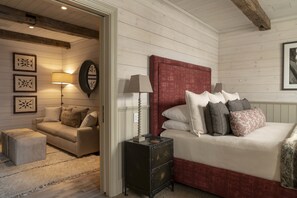 A bedroom with a bed, a nightstand, a lamp, a sofa, and a small table. - Eleven Scarp Ridge Lodge (Crested Butte)