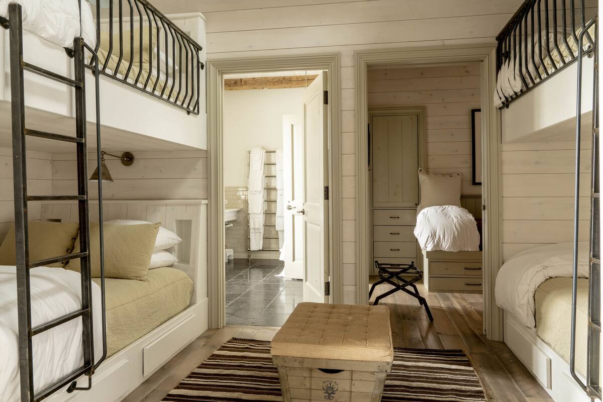 A compact, well-lit room with bunk beds, a small table, and a wardrobe.