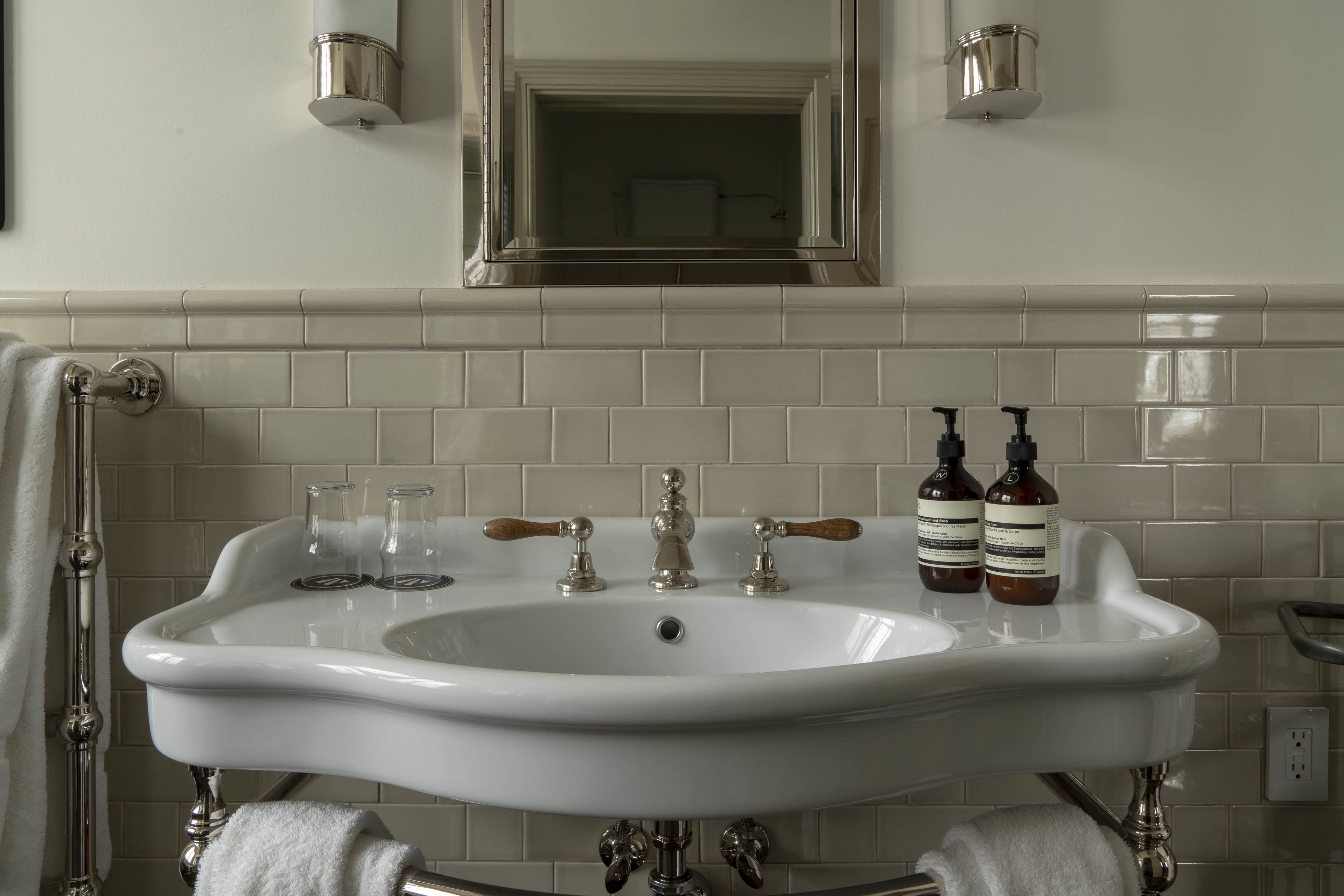 A bathroom with a white sink, two bottles of hand soap, and a mirror above the sink.