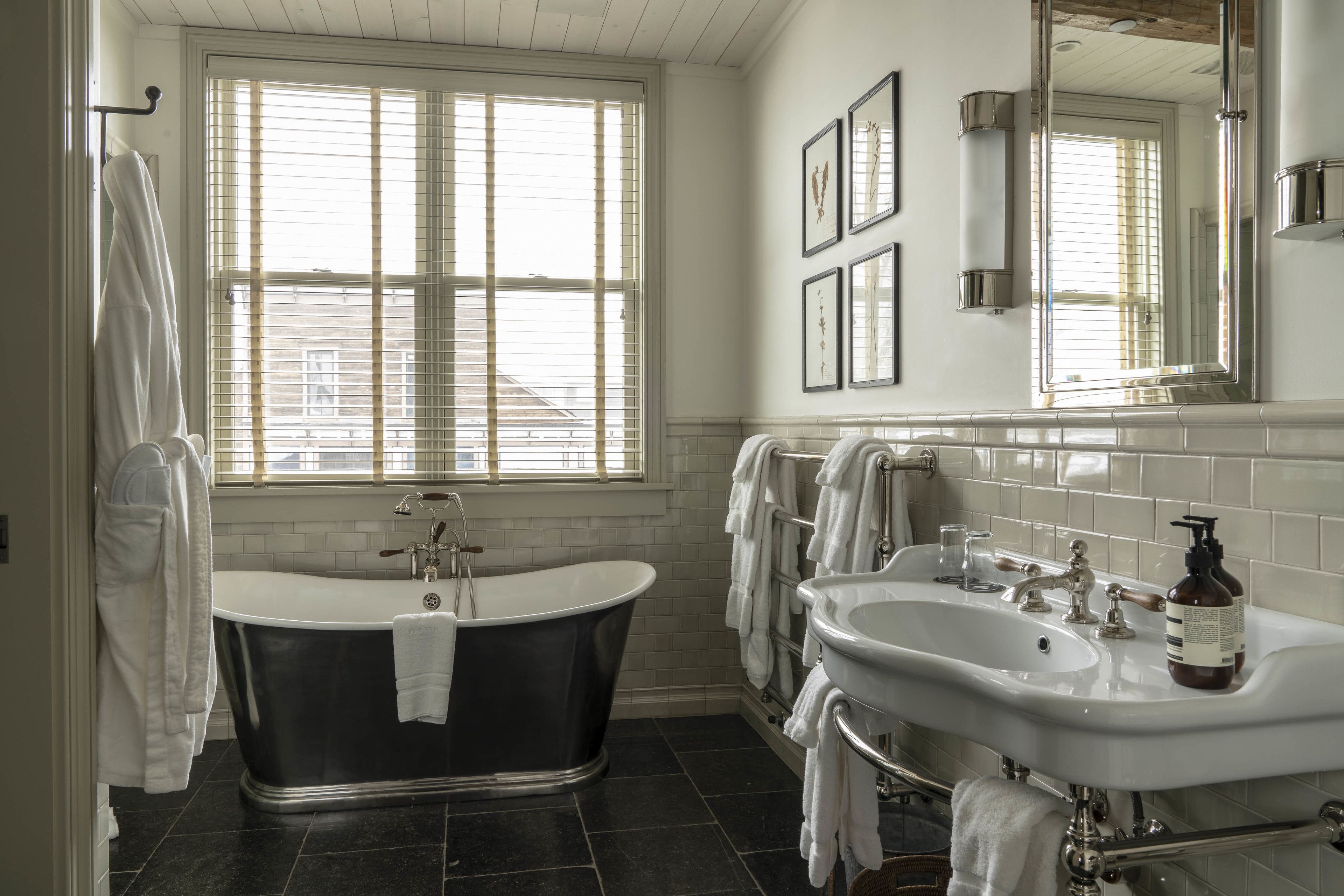 A bathroom with a freestanding bathtub, a double sink vanity, and a large mirror.