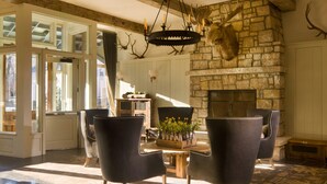 A spacious room with a stone fireplace, leather chairs, and a chandelier with antlers. - Eleven Scarp Ridge Lodge (Crested Butte)