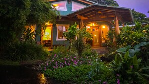 A house surrounded by lush greenery and flowering plants. - Gingerhill Farm Retreat (Kealakekua)