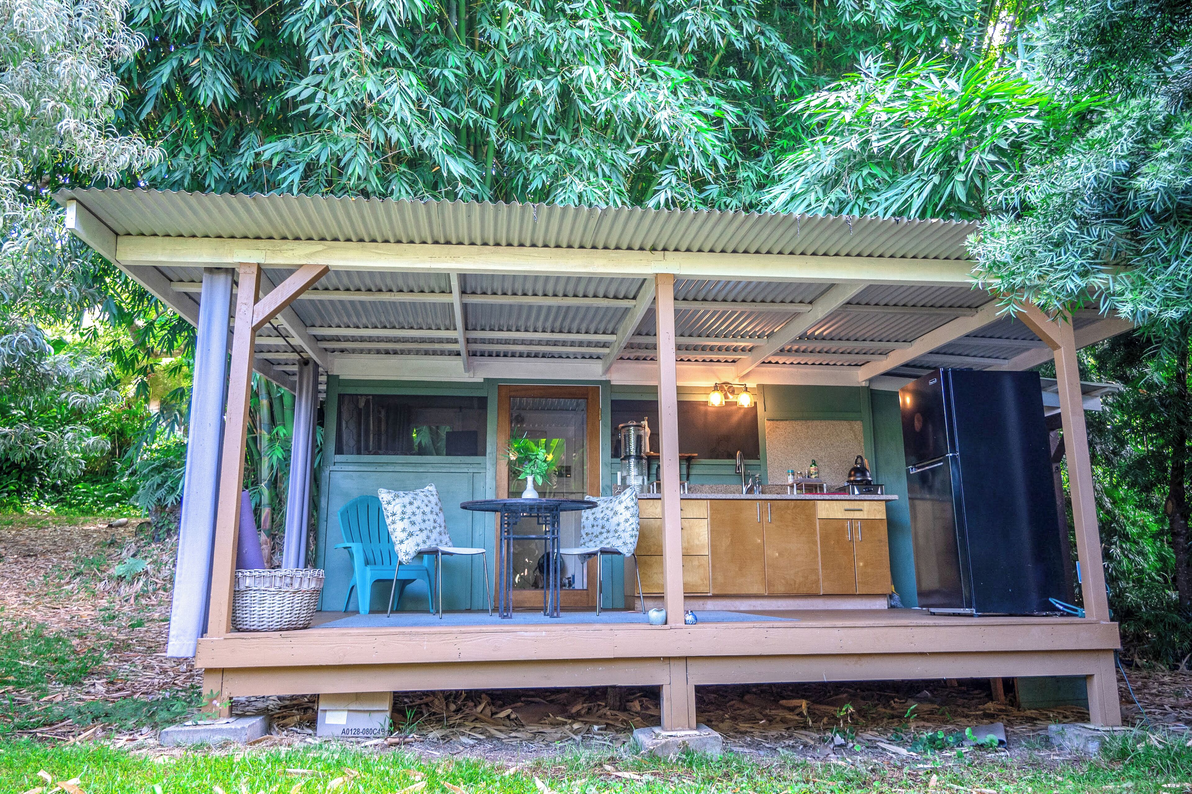 A small, open-air structure with a kitchen area, two chairs, and a table.