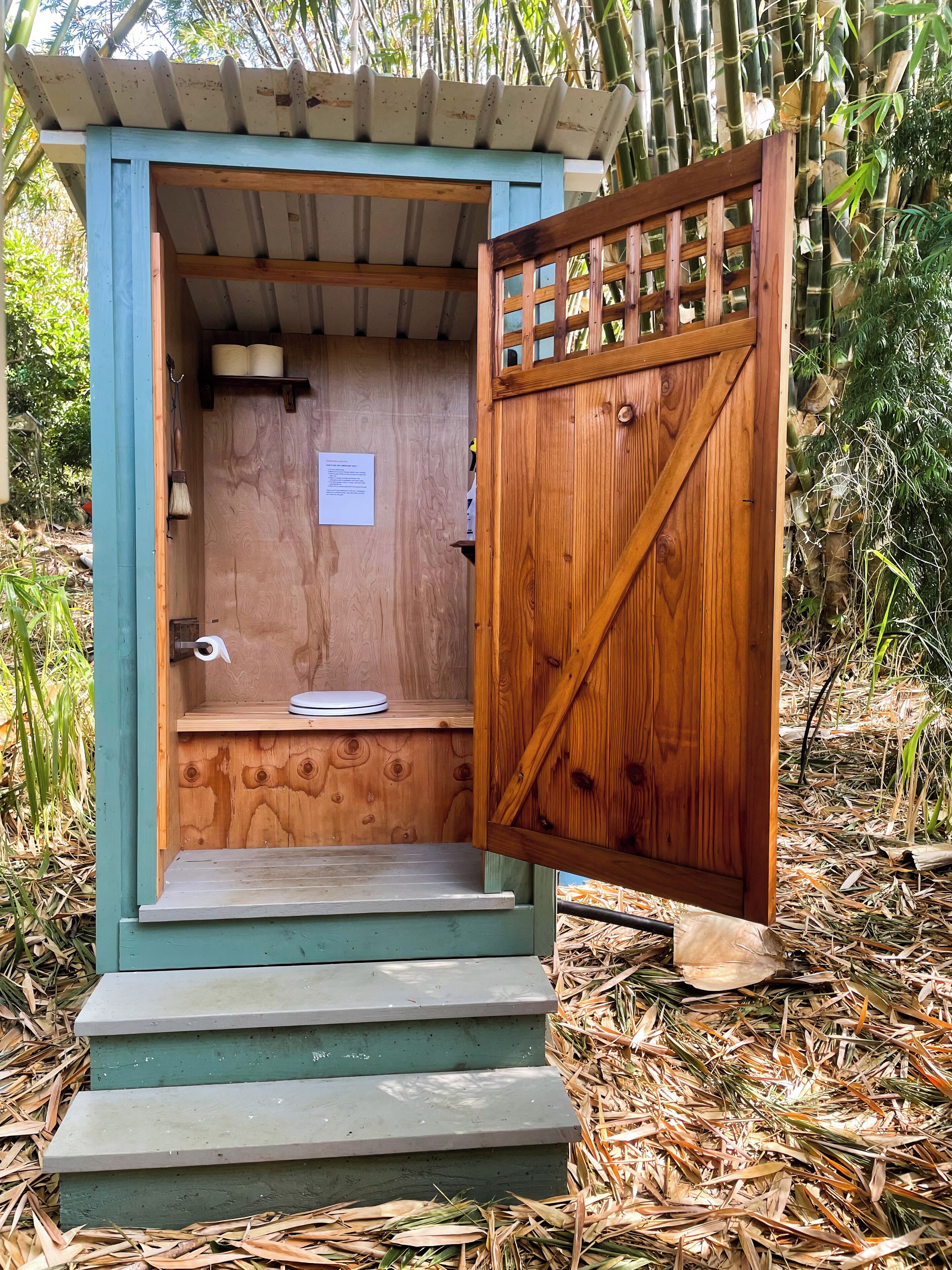 A wooden structure with a door, steps, and a shelf with a broom.