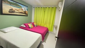 A hotel room with a bed, a painting on the wall, a bright green curtain, and a door. - Jackuri Casa Hospedaje (San Andrés)