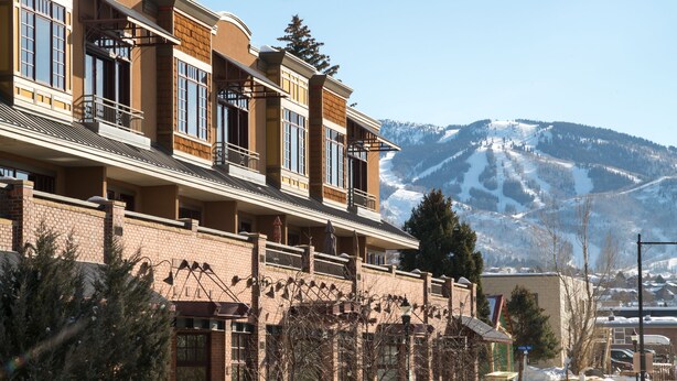 Un hôtel doté de nombreux balcons, d’une façade en briques et offrant une vue sur des montagnes enneigées.