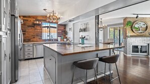 Une cuisine moderne dotée d’un grand îlot central, de tabourets de bar et d’un mur d’accent en bois rustique.