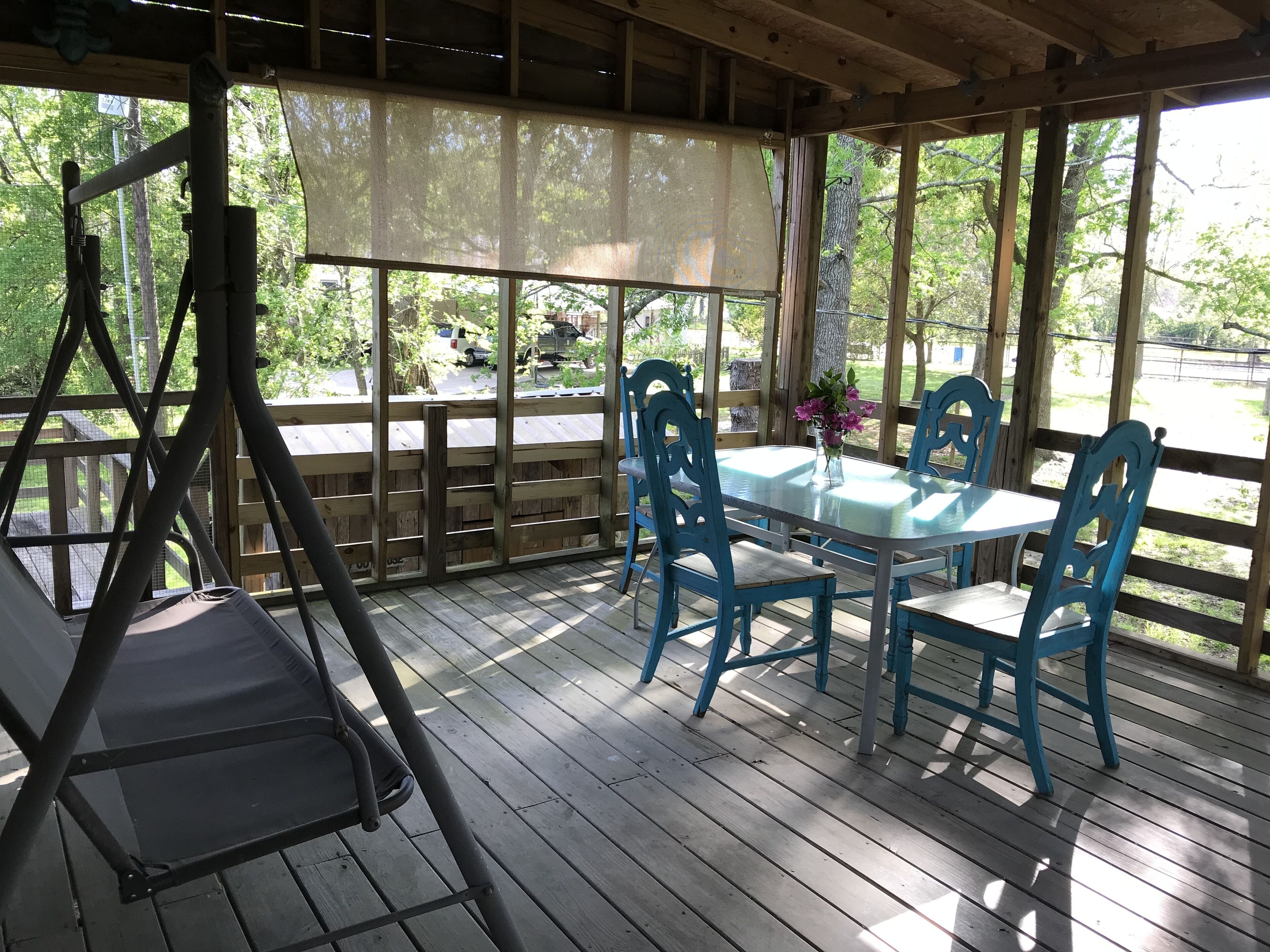 Une terrasse extérieure avec un fauteuil suspendu, une table et des chaises, et une vue sur les environs.