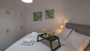 A neatly made bed with white linens, a bedside table with a tray of breakfast items, and a lamp on the nightstand. - Roomy & Comfortable Apt Near Acropolis by GHH (Athens)