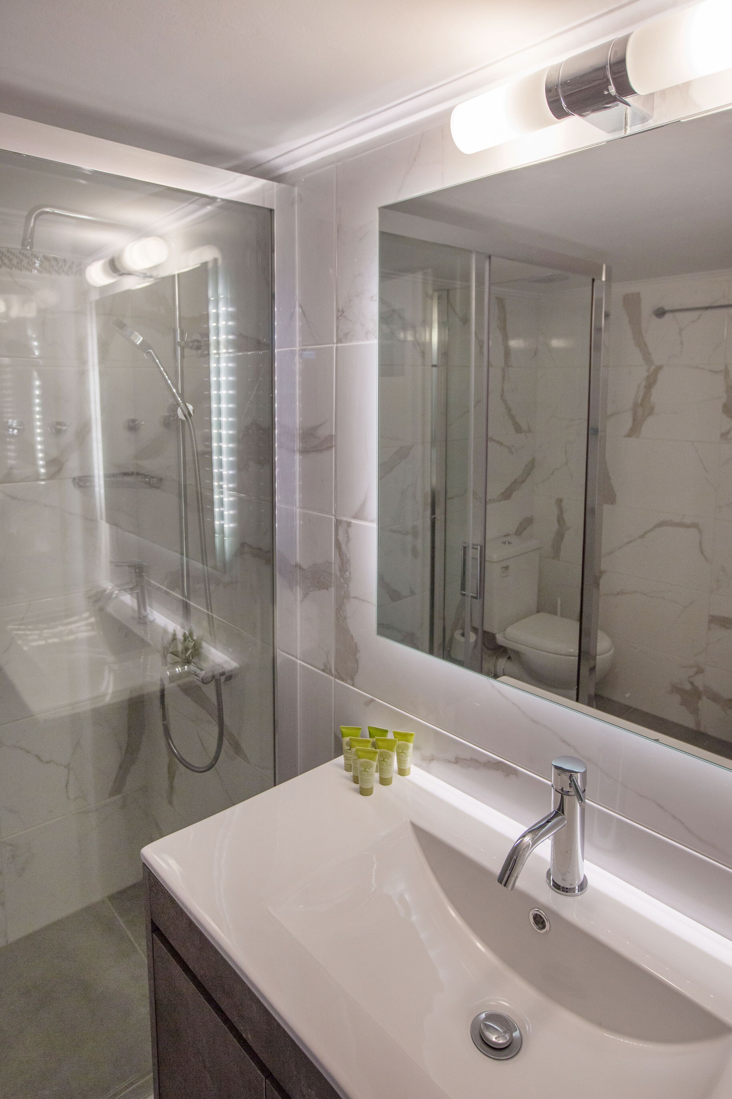 Une salle de bain avec une douche à parois de verre, un lavabo blanc et un grand miroir.