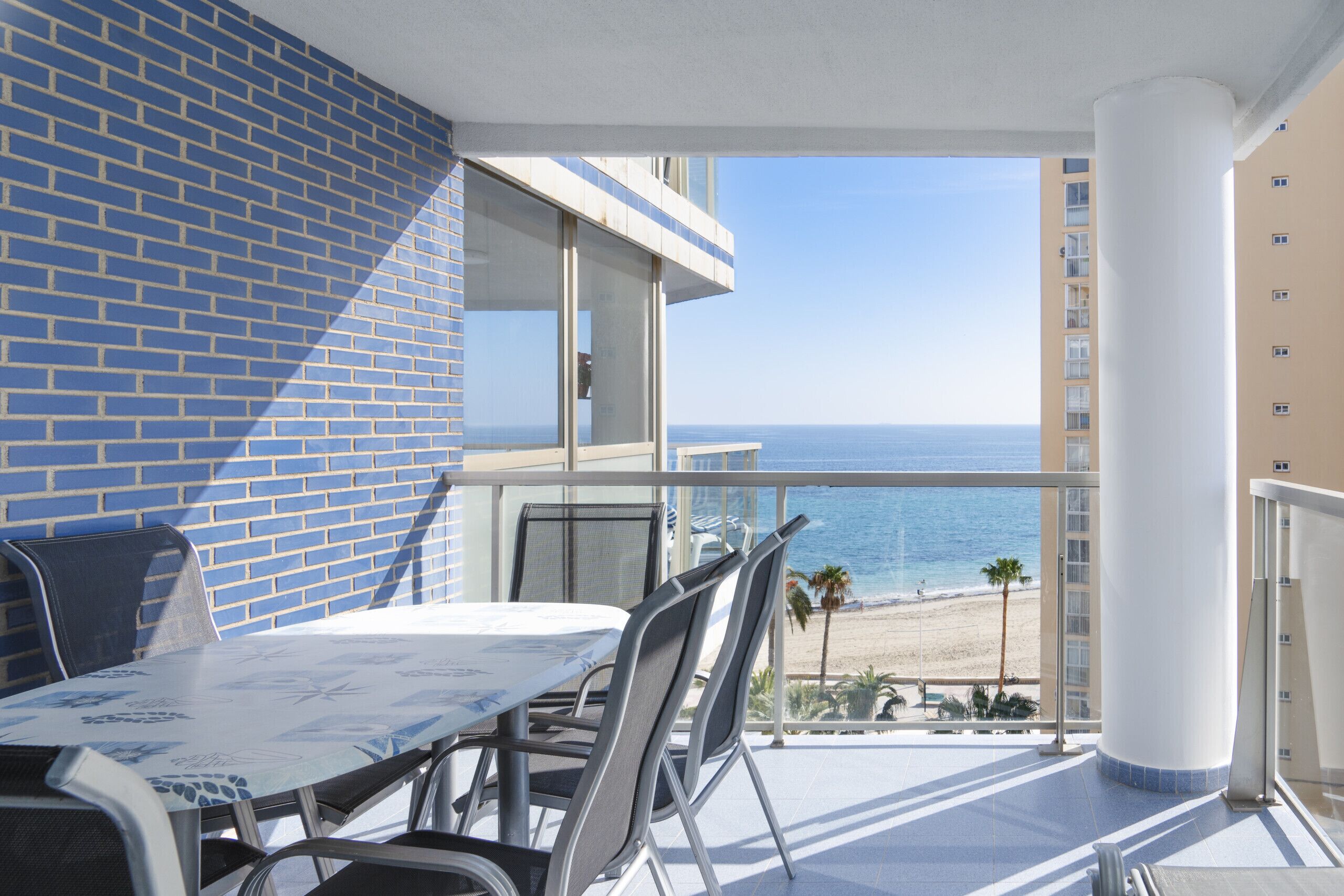 Un balcone con tavolo e sedie, vista sulla spiaggia e sull'oceano.
