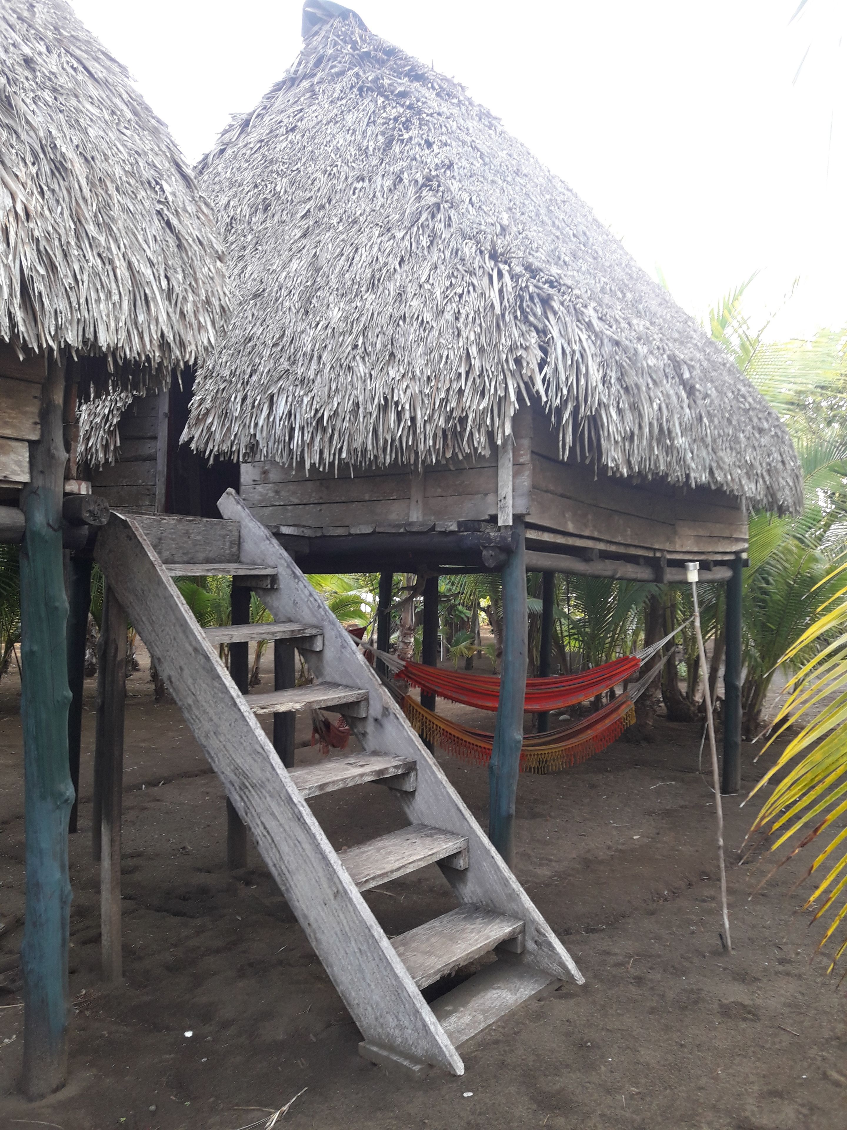 A wooden structure with a thatched roof and a wooden staircase leading to an upper level.