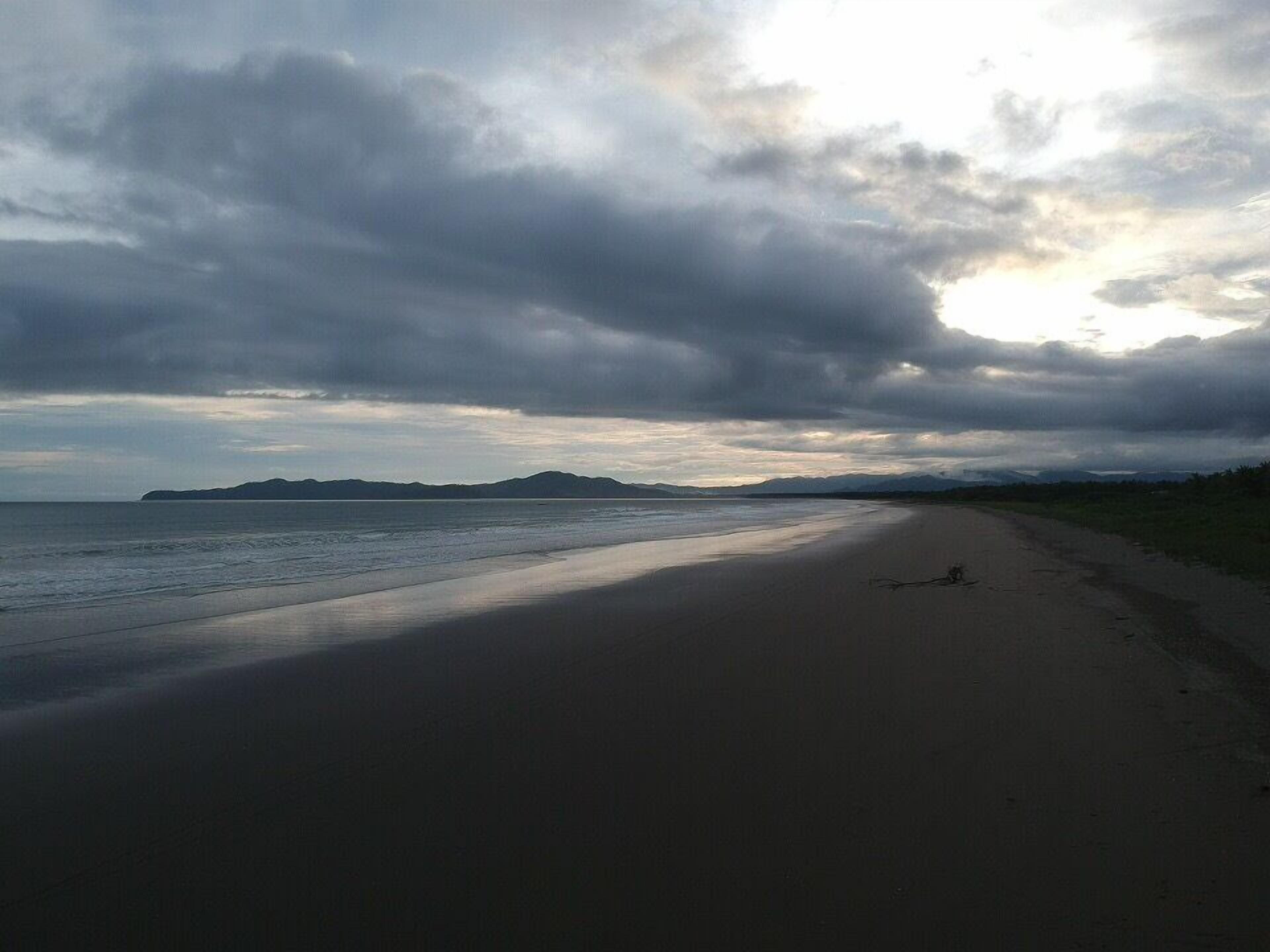 Une plage avec une longue étendue de sable et une mer calme.