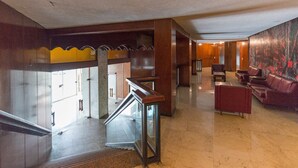 Un hall d’entrée spacieux avec un escalier, un coin salon et une grande peinture abstraite au mur.