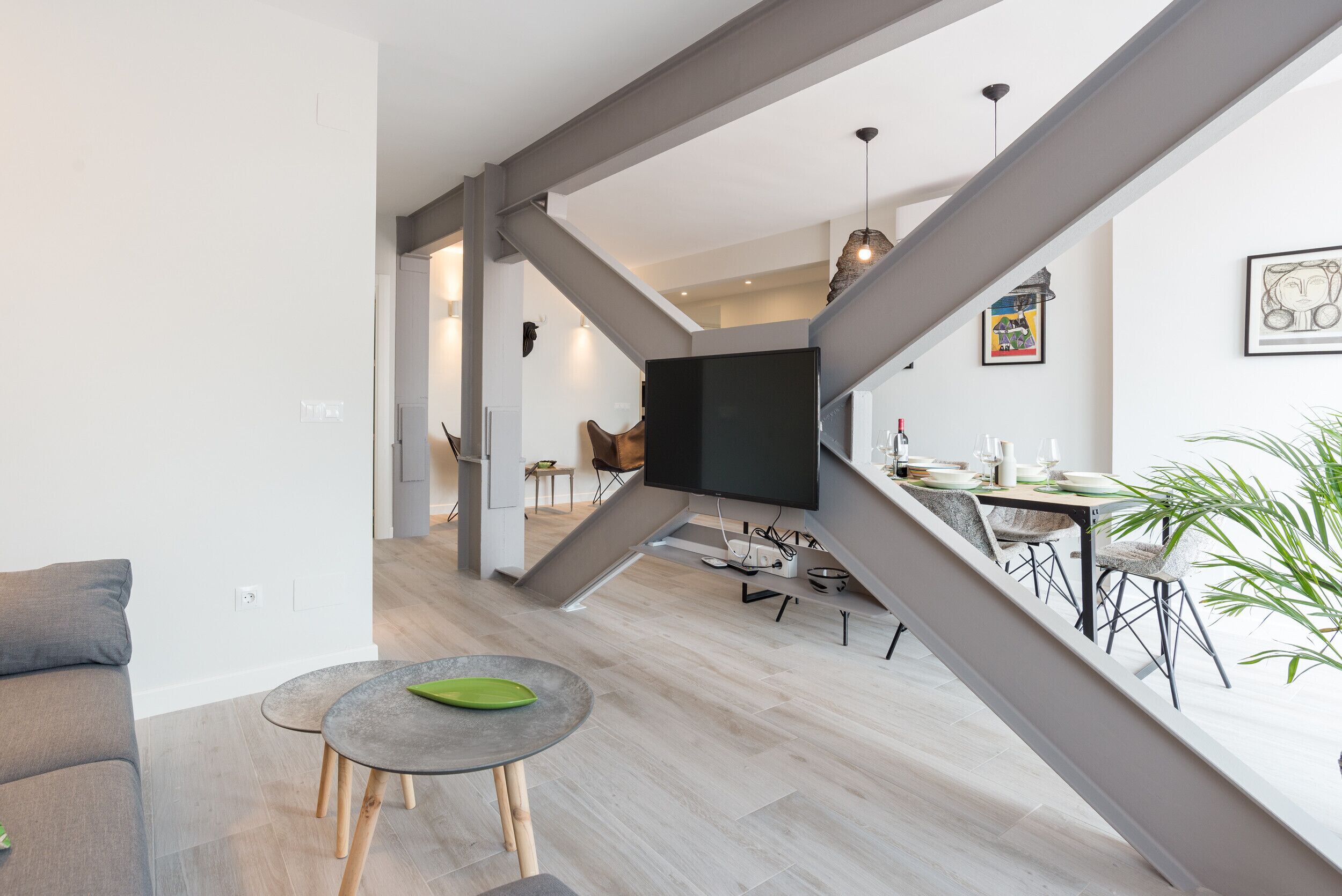 A modern living space with a staircase, a dining area, and a kitchen.