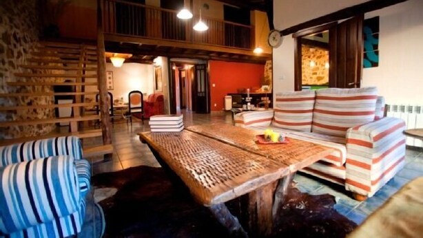 A cozy interior with a wooden table, striped sofa, and a staircase leading to an upper level. - Rural house (Las Mimbres house 1) 10 people Rivera n 4 (Fuentes de Béjar)