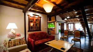 A cozy living room with a red sofa, a small table, and a lamp. There is a staircase leading to another room. - Rural house (Las Mimbres house 1) 10 people Rivera n 4 (Fuentes de Béjar)