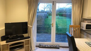 A living room with a television, a dining table, and a kitchen area with a microwave.