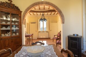 Enjoy meals in this elegant dining room with a long table set for four, featuring a beautiful centerpiece and antique chairs.