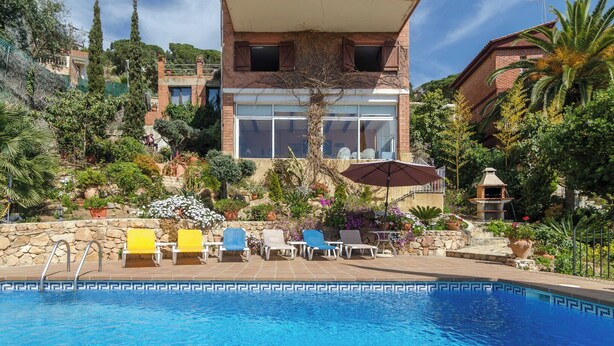 A pool area with lounge chairs and a stone wall.