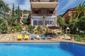 Un espace piscine avec des chaises longues et un mur en pierre.