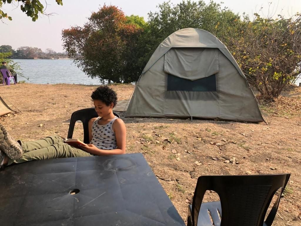 Una carpa montada sobre un terreno de tierra con una mesa y sillas cerca.