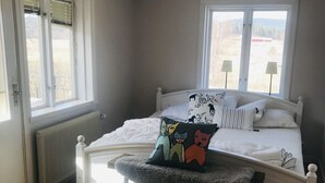 Une chambre à coucher avec un lit, un banc et deux fenêtres.